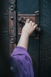 Main d’une personne tenant un doigt coincé dans une porte entrouverte.